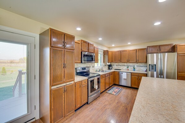 Kitchen features a large island with a granite countertop, double oven, microwave, and refrigerator.