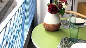 Een kamer met uitzicht op een straat, een vaas met bloemen op een tafel en een lamp.