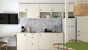 Et moderne køkken med hvide skabe, et flisebaggrund og et spiseområde med et grønt bord og træstole.