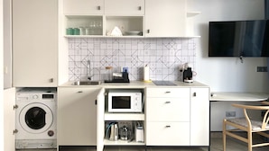 Een moderne keuken met inbouwapparatuur, een wasmachine en een flatscreen televisie.