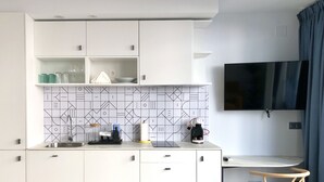 Een moderne keuken met witte kastjes, een betegelde spatwand en een koffieapparaat.