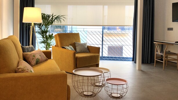 En moderne stue med sofa, lænestol og to borde med metalstel.