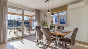 A dining area with a table set for two, chairs, a potted plant, and a window with a view of the outside. - Gorgeous home in Krsan (Krsan)