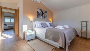 A modern bedroom with a large bed, bedside tables, a wall-mounted air conditioner, and a ceiling light fixture. - Gorgeous home in Krsan (Krsan)