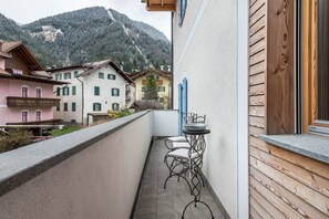 Ein schmaler Balkon mit Tisch und Stühlen, mit Blick auf einen Berg.