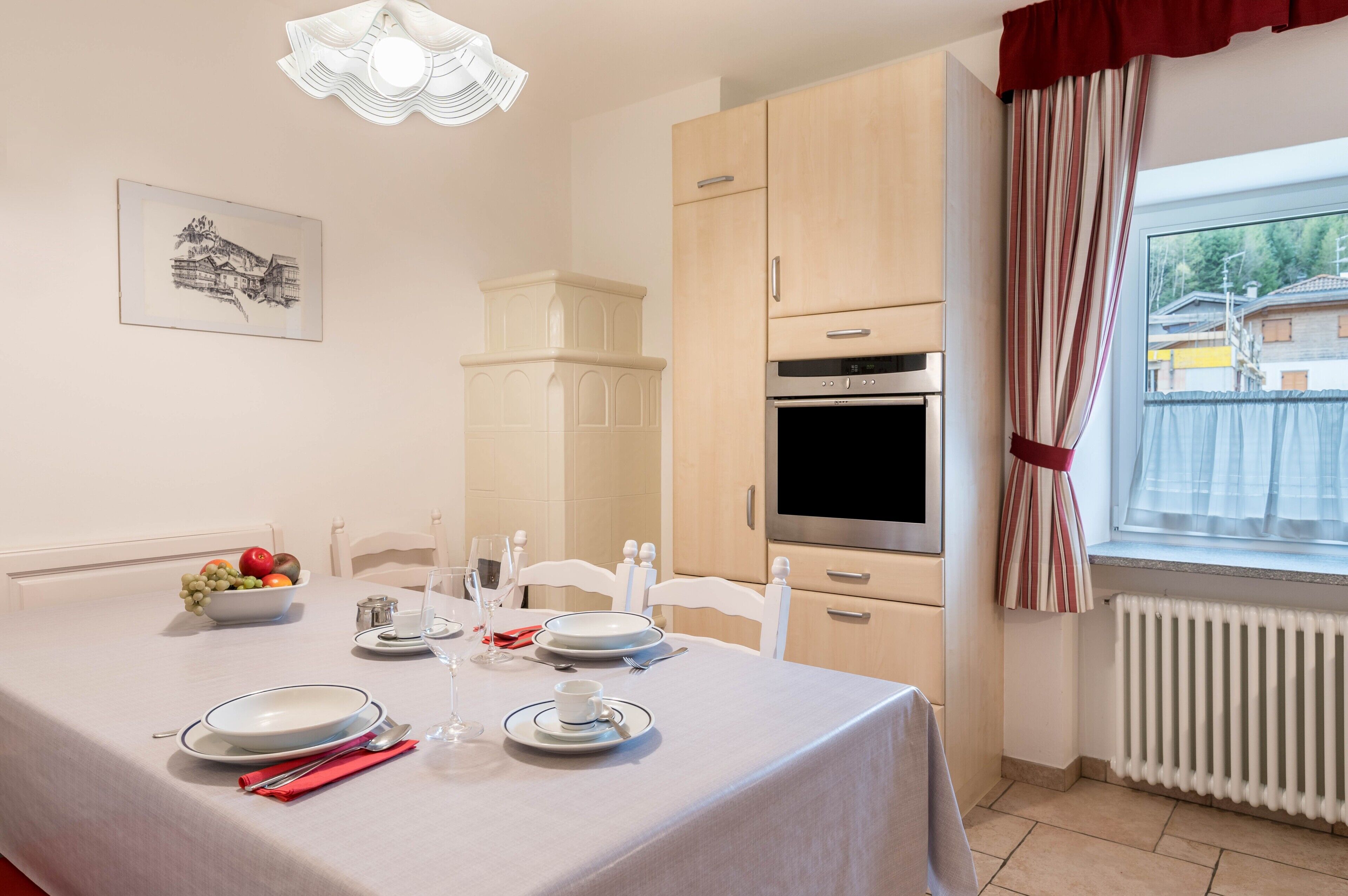 Un comedor con una mesa para dos, microondas y ventana con cortinas.