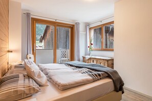 Un dormitorio con cama, escritorio y ventana con cortinas.