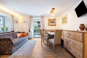 A living room with a sofa, chairs, a wooden cabinet, and a TV mounted on the wall.