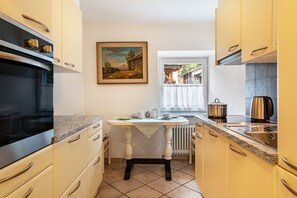 A compact kitchen with a stove, sink, and a dining table set for two.