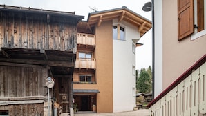 A traditional wooden building with a balcony, a modern building with a beige facade, and a white building with a red railing. - Apartment 'Ciasa Majonade Pozza Di Fassa Tipo1' with Mountain View, Private Terrace and Wi-Fi (Pozza di Fassa)
