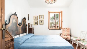 Un dormitorio con cama, ventana, sillón y cómoda.