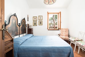 Une chambre à coucher avec un lit, une fenêtre, une chaise et une commode.