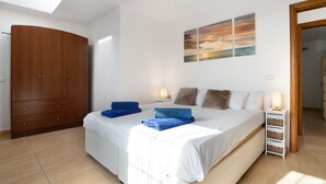A bedroom with a bed, a wardrobe, a nightstand, and a painting on the wall. - Vacation Apartment 'Puerto Chico H' with Shared Pool, Private Terrace and Wi-Fi (Playa Blanca)