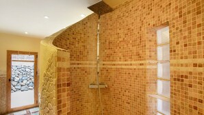 Eine Dusche mit gefliesten Wänden, einem Fenster und einer Tür zu einem Außenbereich.