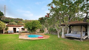 Ein Garten mit Schwimmbecken, einem Bett und einem Baum.
