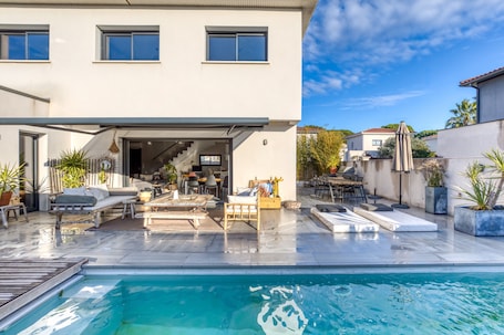 A modern house with a swimming pool, outdoor furniture, and a patio area.