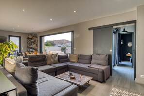 Un salon moderne comprenant un canapé d’angle, une table basse et un coin repas avec des chaises et une table.