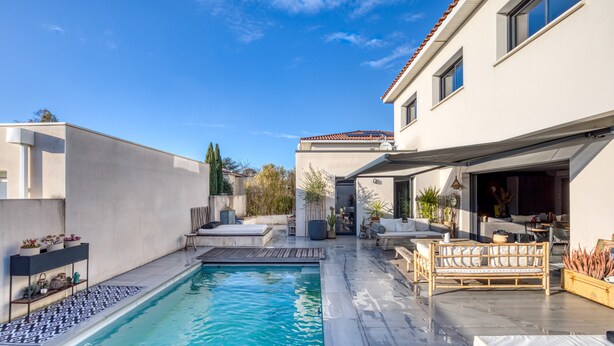 A modern house with a swimming pool, outdoor seating, and a patio area.