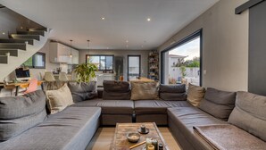 A modern living room with a sectional sofa, a coffee table, and a staircase.