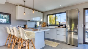 A modern kitchen with white cabinetry, a stainless steel refrigerator, and a central island with bar stools.