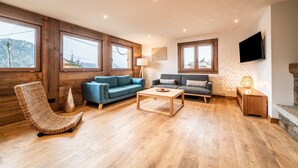 Una sala de estar con paredes de madera, dos sofás, una mesa de centro, un televisor y una chimenea.
