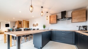 Una cocina moderna con una isla central, armarios oscuros e iluminación colgante.