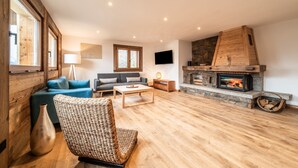 Una sala de estar con chimenea, sofás, una mesa de centro y televisor.