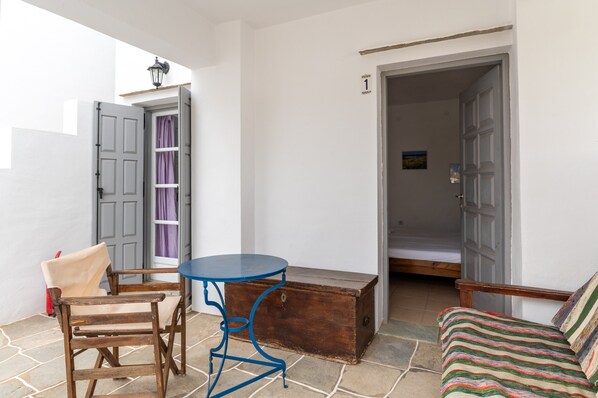 A room with a wooden chest, a blue table, and a chair. - Studio Apartment 'Sifnos 1' with Sea View, Wi-Fi and Air Conditioning (Sifnos)