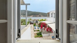 Une porte ouverte donnant sur un patio avec vue sur la mer et une colline.