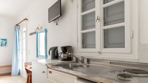 Een keuken met een spoelbak, fornuis en een televisie erboven.