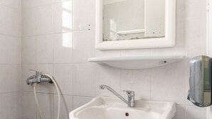 Ein Badezimmer mit einem weißen Waschbecken, einem Spiegel darüber und einem Händetrockner zur Rechten.