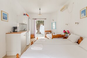 A bedroom with a bed, bedside table, and a view of a tree through an open door.