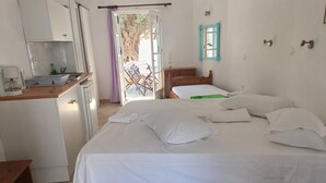 Un dormitorio con cama, una mesita de noche de madera, una pequeña mesa, una silla y vistas al exterior.