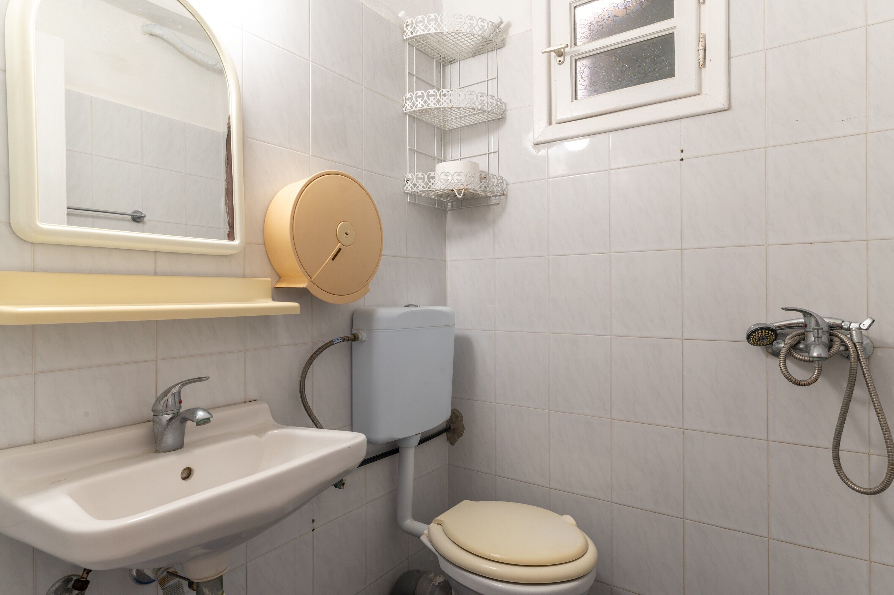 A bathroom with a sink, toilet, mirror, and shower.