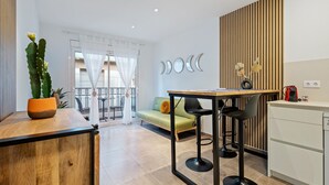 A modern kitchen with a wooden countertop, a dining table, and a bar stool. - Apartment 'Mabicarent Playa 2' with Private Terrace, Wi-Fi and Air Conditioning (Calafell)