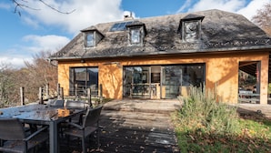 Une maison dotée d’une grande terrasse, d’un coin repas et d’un espace extérieur abrité.