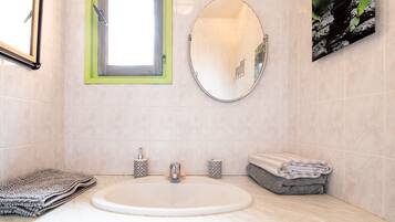 A bathroom with a sink, mirror, window, and towel storage.