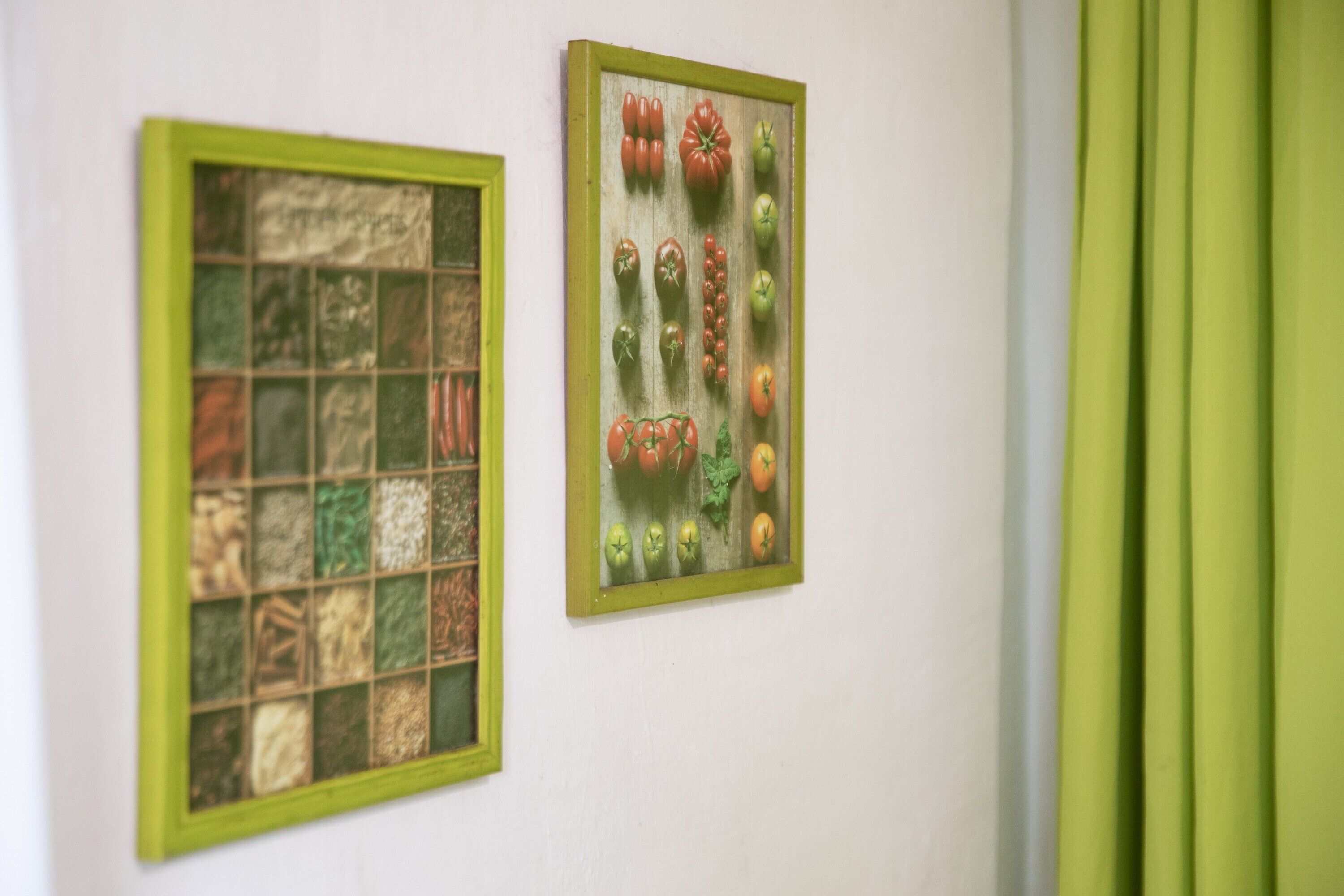 Twee ingelijste kunstwerken aan een muur, waarvan één een mozaïek toont en de andere een verzameling groenten.