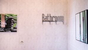 A bathroom sign with a modern design, a tiled wall, and a framed picture.
