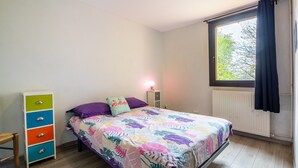 A bedroom with a bed, dresser, window, and radiator.
