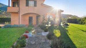 A two-story house with a stone pathway leading to the entrance, surrounded by a well-maintained lawn and garden. - Apartment 'Ca' Du Barba' with Private Terrace, Private Garden and Wi-Fi (Taggia)