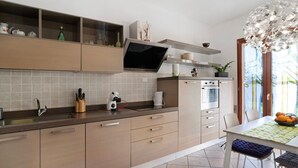 A modern kitchen with a built-in oven, a microwave, and a large window. - Apartment 'Ca' Du Barba' with Private Terrace, Private Garden and Wi-Fi (Taggia)