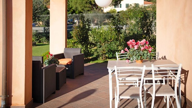 An outdoor patio with a table and chairs, surrounded by greenery and a view of a house. - Apartment 'Ca' Du Barba' with Private Terrace, Private Garden and Wi-Fi (Taggia)