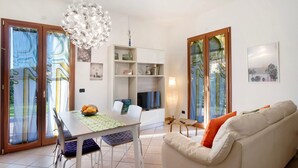 A modern living room with a dining table, sofa, and a TV. - Apartment 'Ca' Du Barba' with Private Terrace, Private Garden and Wi-Fi (Taggia)