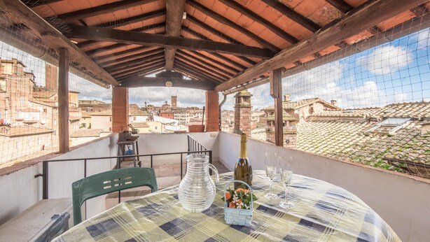 Un balcon avec une table dressée pour deux personnes, une bouteille et un verre d’eau.