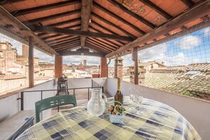 A balcony with a table set for two, a bottle, and a glass of water. - Apartment 'Il Campo Comfort Apt with Balcony' with Private Terrace, Wi-Fi and Air Conditioning (SIENA)