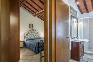 Une chambre à coucher avec un lit, une porte en bois et une salle de bain équipée d’un lavabo et d’un miroir.