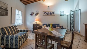 Un coin repas comprenant une table en bois, des chaises, un canapé et une lampe.