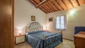 Une chambre à coucher avec un lit, une tête de lit en bois, des tables de chevet et une fenêtre.