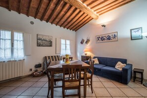 A dining area with a wooden table and chairs, a blue sofa, and a tiled floor.
